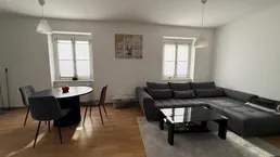 Heller Wohn- und Essbereich mit modernem Sofa, Esstisch und Parkettboden.