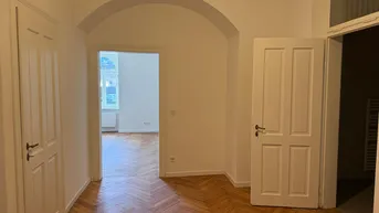 Heller Flur mit Fischgrätparkettboden und weißen Türen, der zu weiteren Räumen führt.