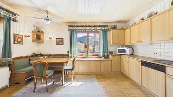 Gemütliche Wohnküche im Landhausstil mit Holzeinbauten, Essbereich und weitem Bergblick.
