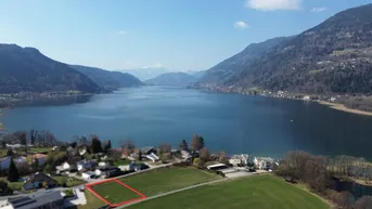 Luftaufnahme eines Baugrundstücks mit weitem Blick auf den See und die umliegende Berglandschaft.