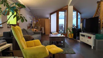 Helles Wohnzimmer mit gemütlicher Einrichtung, Holzboden und Zugang zu einer Dachterrasse.