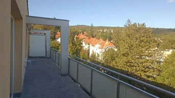 Geräumiger Balkon mit Fliesenboden und weitem Blick ins Grüne und auf umliegende Häuser.