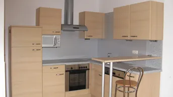 Funktionale Einbauküche mit hellen Holzfronten, integrierten Geräten und einer praktischen Frühstücksbar.
