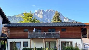 Charmantes Haus mit Holzelementen, Balkon und atemberaubendem Bergblick in ländlicher Umgebung.