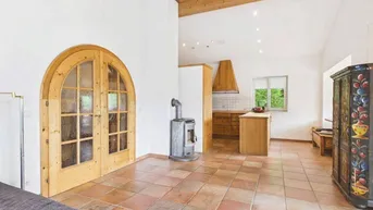 Gemütlicher Wohnbereich mit Kaminofen, Terrakottafliesen und Holzbalkendecke.