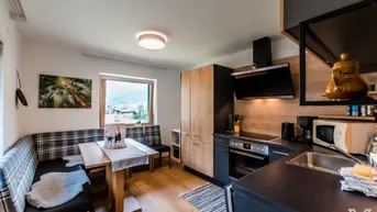 Moderne Küche mit Holzelementen, Essbereich und Blick auf die umliegende Landschaft.
