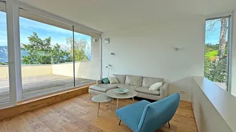 Helles Wohnzimmer mit Holzboden, bequemer Couch und großen Fenstern mit Bergblick und Terrassenzugang.