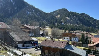 Malerischer Blick auf ein Bergdorf mit traditionellen Häusern und schneebedeckten Gipfeln.