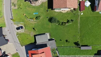 Luftaufnahme des Grundstücks mit umliegenden Häusern, viel Grünfläche und einem geparkten Auto.