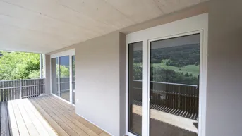 Geräumiger Balkon mit Holzboden und weitem Blick über die grüne Landschaft.