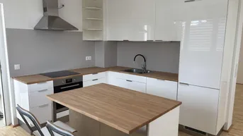Moderne Küche mit weißen Hochglanzfronten, Holzarbeitsplatten und einer Kücheninsel mit Sitzgelegenheiten.