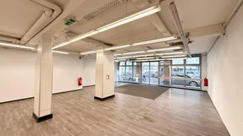 Eingangsbereich des Gewerberaums mit breiter Glasfront und hellem Laminatboden.