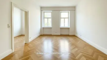 Helles, leeres Wohnzimmer mit Fischgrätparkett und zwei großen Fenstern.