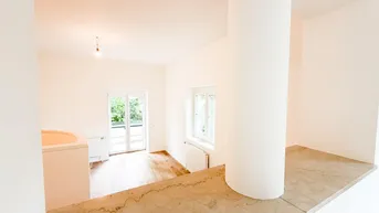 Heller Wohnbereich mit Holzfußboden, runder Säule und Zugang zu einem Balkon oder einer Terrasse.