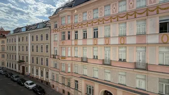 Historisches Wohngebäude mit dekorierter Fassade, Balkonen und Blick auf die Straße.