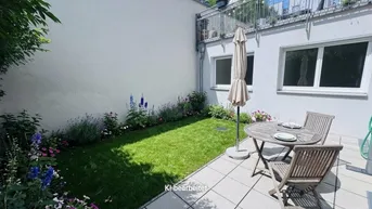 Gepflegte Terrasse mit Gartenmöbeln, Sonnenschirm und einem kleinen Rasenbereich mit Blumenbeeten.
