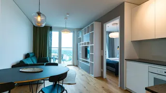 Moderner offener Wohnbereich mit Holzboden, Essbereich und integrierter Küche, mit Zugang zum Balkon.