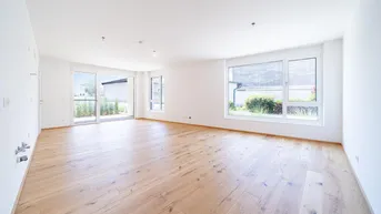 Helles, geräumiges Wohnzimmer mit großen Fenstern, Holzboden und Zugang zur Terrasse.