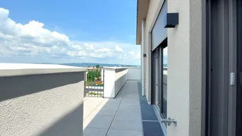 Lange, schmale Dachterrasse mit Fliesenboden und weitem Blick in die grüne Landschaft.
