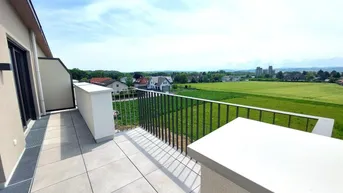 Geräumiger Balkon mit Fliesenboden und weitem Blick über grüne Felder und die Umgebung.