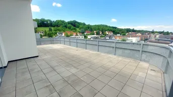 Große geflieste Terrasse mit weitem Blick über die umliegende Landschaft und Häuser.