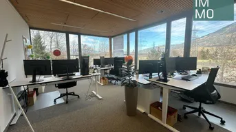 Geräumiges Großraumbüro mit mehreren modernen Arbeitsplätzen, großen Fenstern und Bergblick.