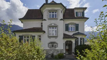 Repräsentative Fassade einer historischen Villa mit traditionellen Fensterläden und gepflegtem Vorgarten.