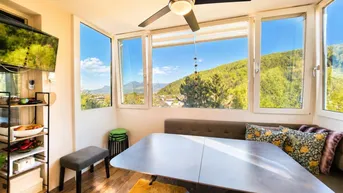Helles Esszimmer mit Panoramablick auf die Berge und grüne Landschaft durch große Fenster.