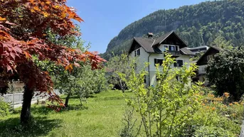 Großzügiger Gartenbereich mit altem Baumbestand und Blick auf die umliegende Berglandschaft.