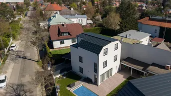 Moderne Villa mit Pool und Garten in einer ruhigen Wohngegend aus der Vogelperspektive.
