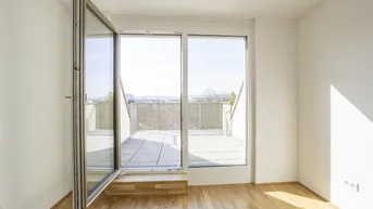 Helles Zimmer mit Holzboden und Zugang zu einer großen Terrasse mit Weitblick.