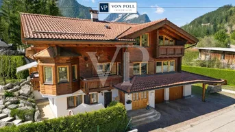 Traditionelles Holzchalet mit mehreren Balkonen, Ziegeldach und Bergblick in alpiner Umgebung.