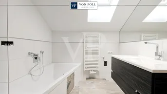 Modernes Badezimmer mit Badewanne, Waschtisch, großem Spiegel und Dachfenster.