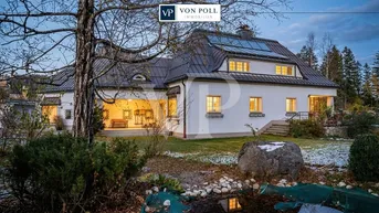Elegantes Landhaus mit weißer Fassade, großem Garten und Teich in idyllischer Umgebung.