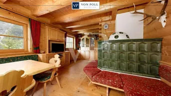 Traditionelles Wohnzimmer im alpinen Stil mit Kachelofen, Holzboden und rustikalen Möbeln.