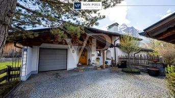 Traditionelles Haus im alpinen Stil mit Garage, gepflasterter Auffahrt und Bergblick.