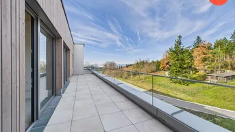 Weitläufige Terrasse mit Fliesenboden und Glasgeländer, bietet einen weiten Blick in die Natur.