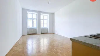 Helles Zimmer mit Fischgrätparkettboden und zwei großen Fenstern, ideal als Wohnbereich.