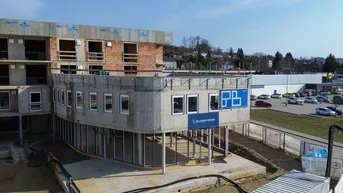 Neubau im Bau mit sichtbaren Beton- und Ziegelstrukturen, umgeben von einer Baustelle.