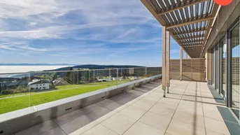 Große Dachterrasse mit Holzdach und Glasgeländer bietet einen weiten Blick über die Landschaft und die Wolken.