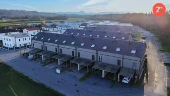 Luftaufnahme einer modernen Reihenhaussiedlung mit Carports und Grünflächen.