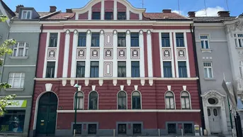 Historisches Gebäude mit roter Fassade und weißen vertikalen Streifen, klassische Architektur.