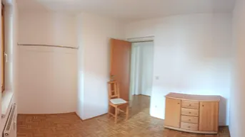 Helles Schlafzimmer mit Parkettboden, Fenster und einem Kleiderständer, bereit zur individuellen Einrichtung.