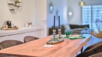 Helles Esszimmer mit rustikalem Holztisch und Blick in den offenen Wohnbereich.