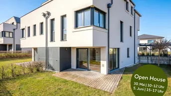 Modernes Reihenhaus mit weißer Fassade, Holzterrasse und kleinem Gartenbereich.