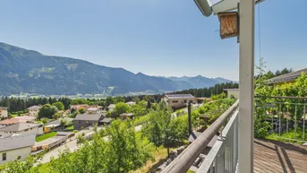 Geräumiger Balkon mit Holzboden und atemberaubendem Blick auf die umliegende Berglandschaft und das Tal.