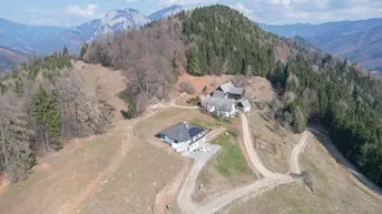 Luftaufnahme von mehreren Gebäuden in einer bergigen Landschaft mit viel Grün.