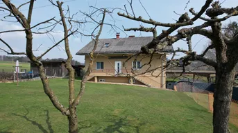 Freistehendes Haus mit großem Garten und ländlichem Ausblick unter blauem Himmel.