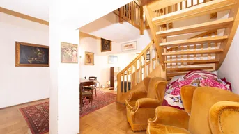Geräumiger Wohnbereich mit Holztreppe, Parkettboden und traditionellen Möbeln, der Gemütlichkeit ausstrahlt.