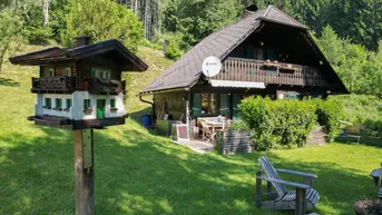 Traditionelles Holzhaus im Chalet-Stil mit möblierter Terrasse und großem Gartenbereich.